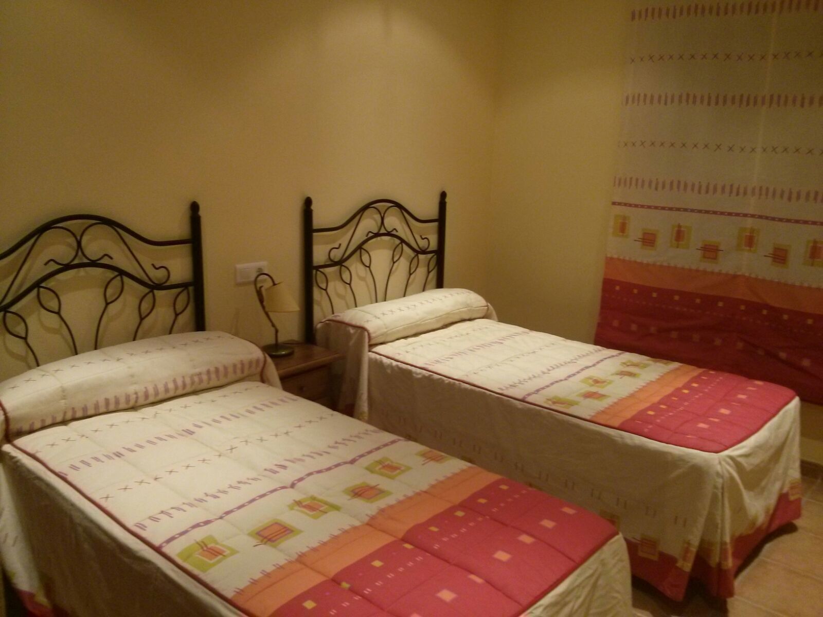 A room with two single beds, each with a patterned bedspread.