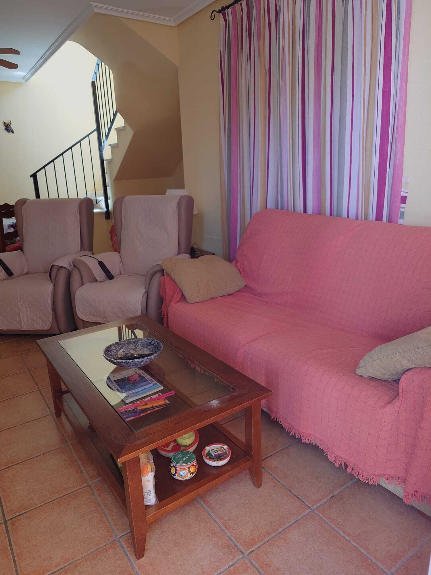 A living room with a sofa, armchairs, a coffee table, and a staircase in the background.