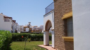 A residential area with a white building featuring a brick facade, a balcony, and a window with bars. - VILLA ALANDALUS VERA PLAYA (Vera playa)