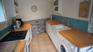 Une cuisine de taille réduite, équipée d’une cuisinière, d’un évier et d’un lave-linge.