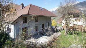 Une maison avec un toit en pente, une cheminée et une petite fenêtre.