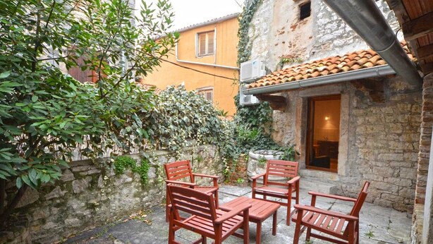 A courtyard with stone flooring, wooden chairs, and a stone wall. - Il Cortile Apartment in Rovinj centre (Rovinj)