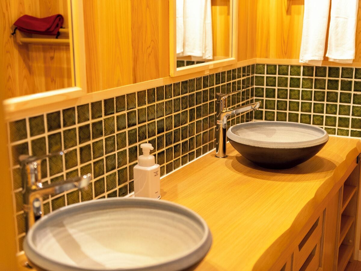 A bathroom with two sinks, a mirror, and a soap dispenser.