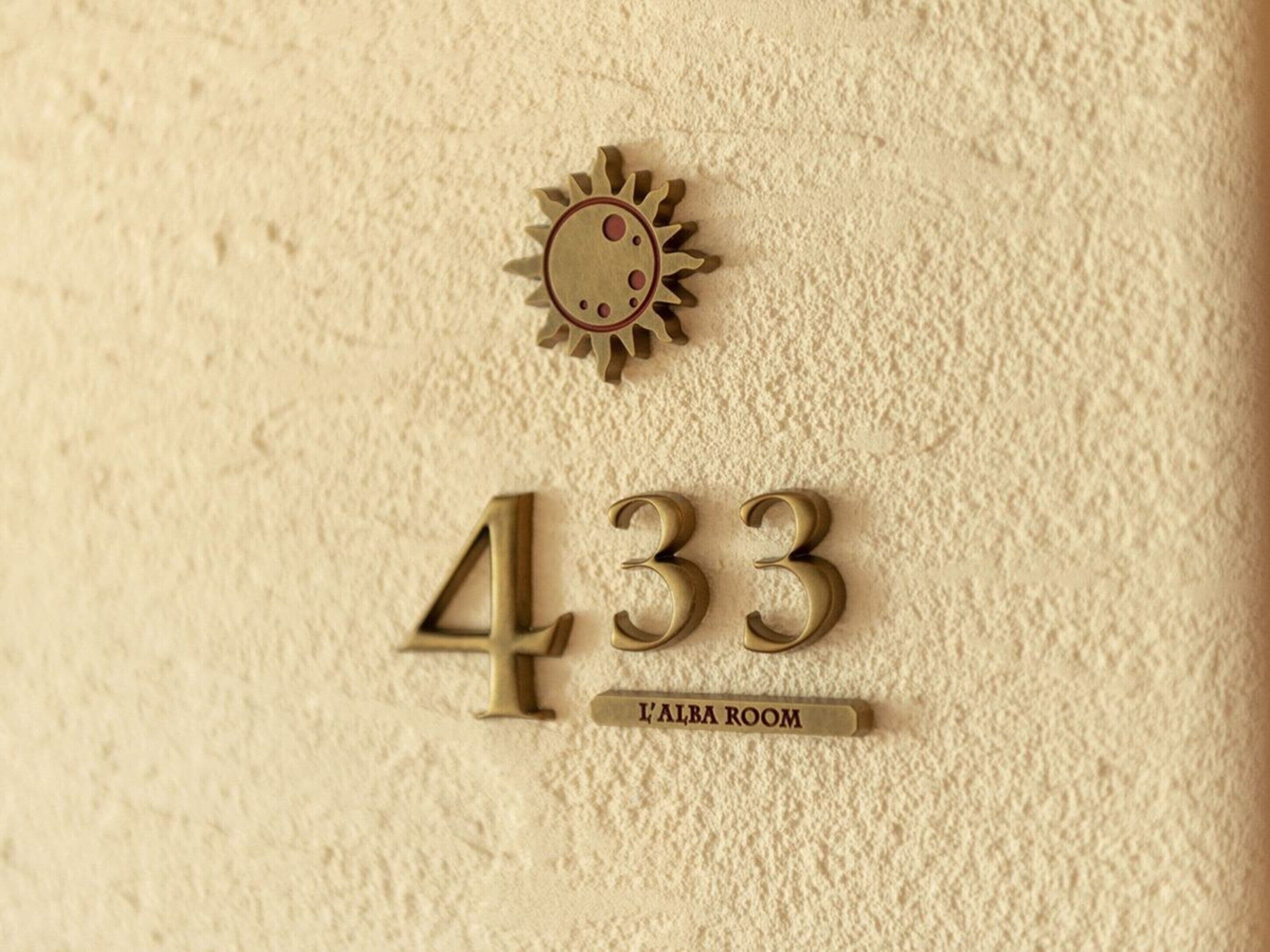 A textured wall with the number 433 and the text 'L'ALBA ROOM' indicating a hotel room number and name.