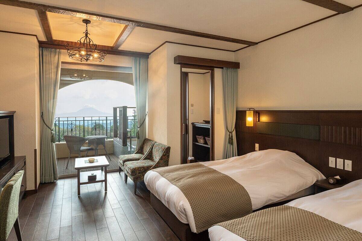 Een hotelkamer met balkon, een bed, bureau en stoel.