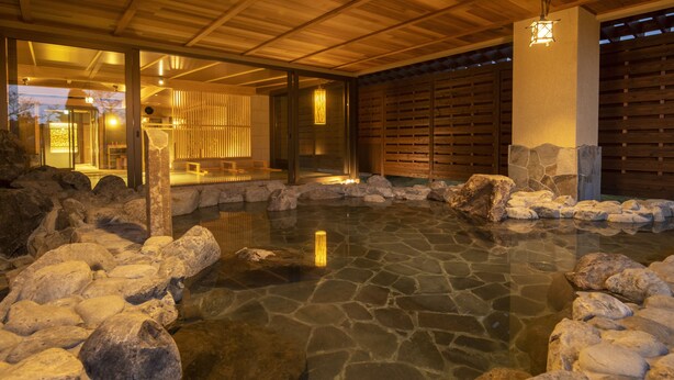 A stone hot spring surrounded by rocks and wooden structures. - LA VISTA Kirishima Hills (Kirishima)