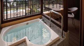Habitación en un piso superior con balcón descubierto, jacuzzi y mobiliario exterior.