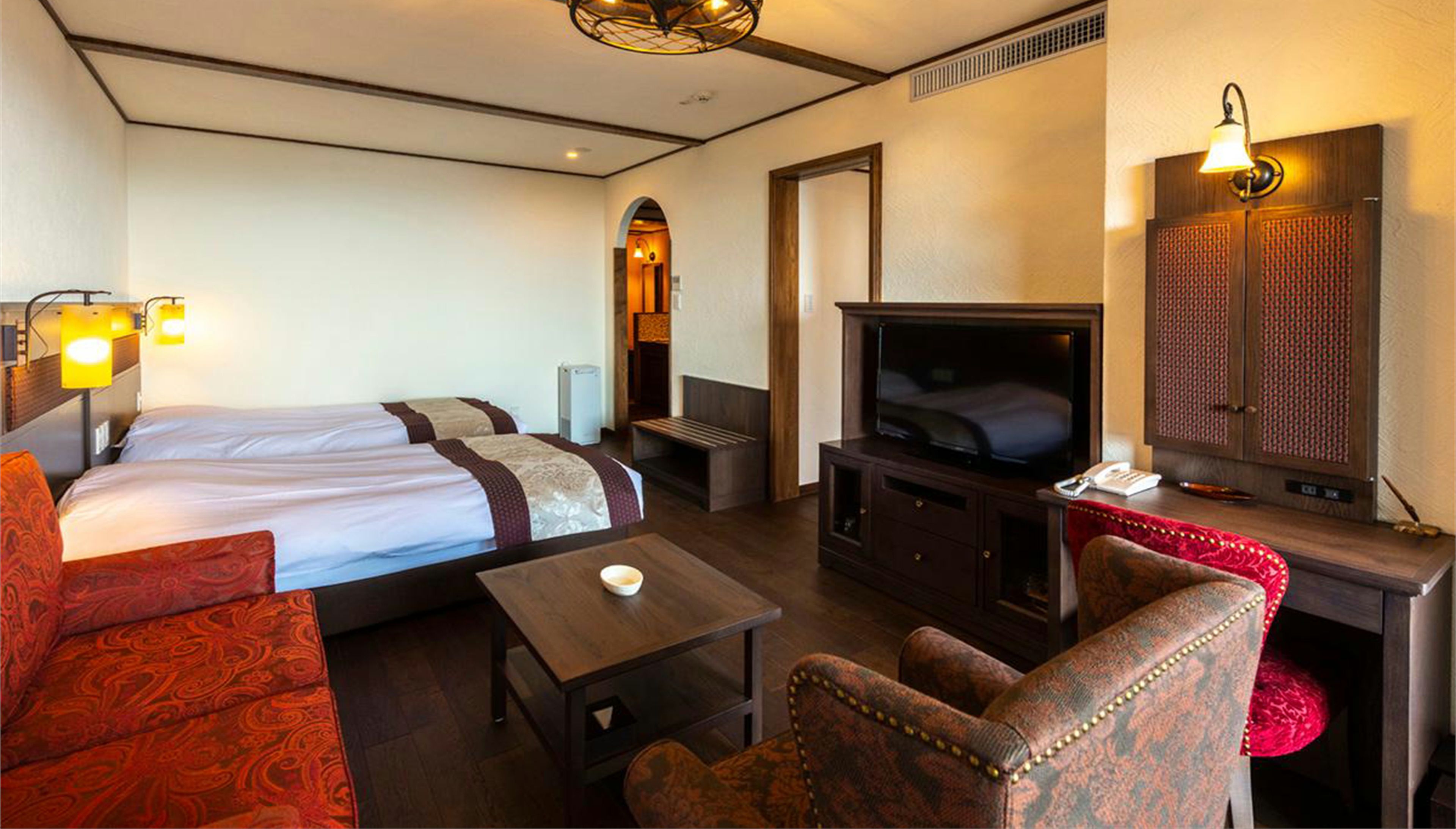 Une chambre quadruple comprenant un lit, une télévision, un coin salon et un miroir.