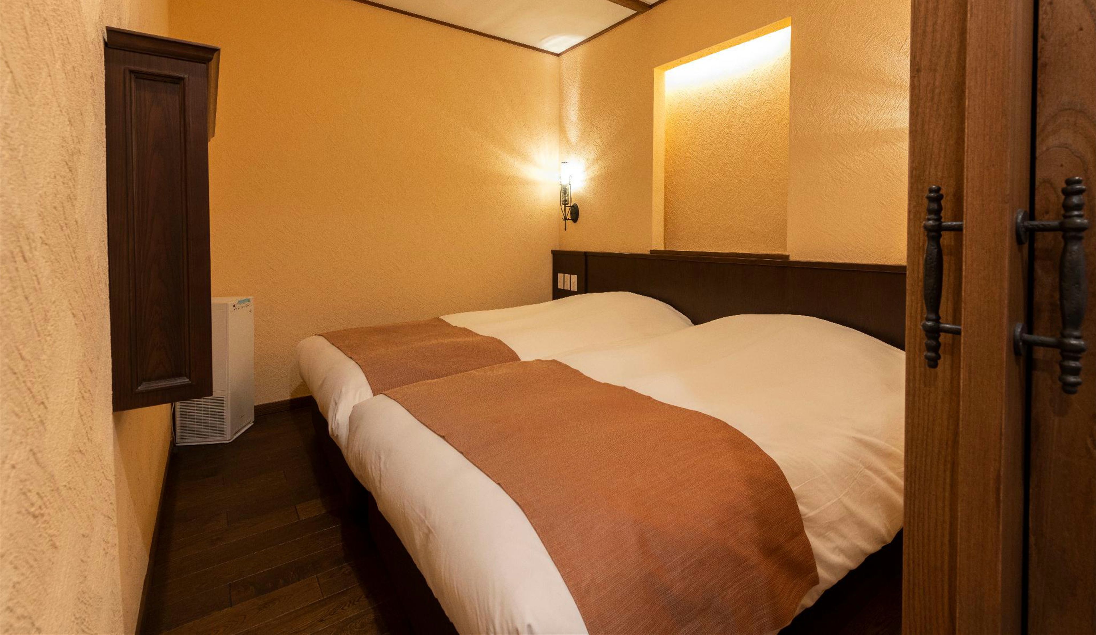 A bedroom with a bed, a wall-mounted light, and a door.