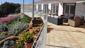 A rooftop patio with outdoor seating, a water feature, and a variety of plants.