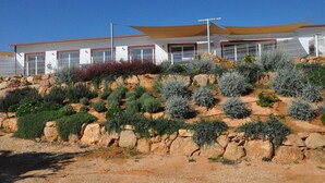 A modern building with a flat roof, large windows, and a stone retaining wall with vegetation.