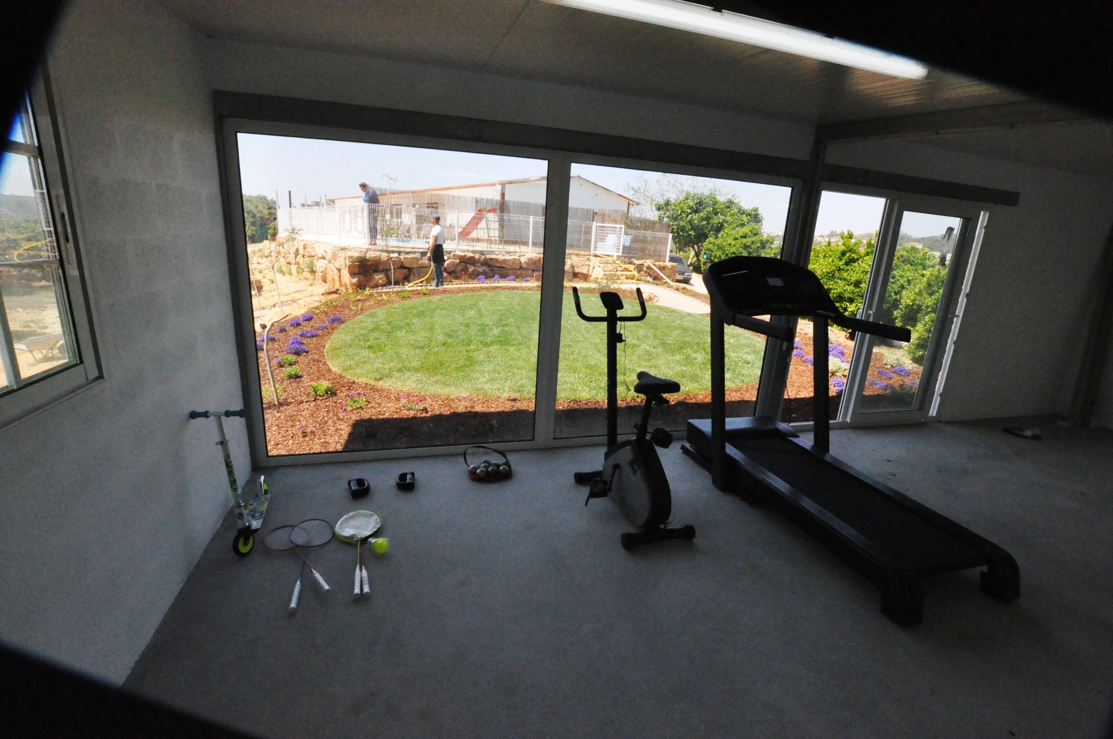 A home gym with exercise equipment, including a treadmill, stationary bike, and weights.