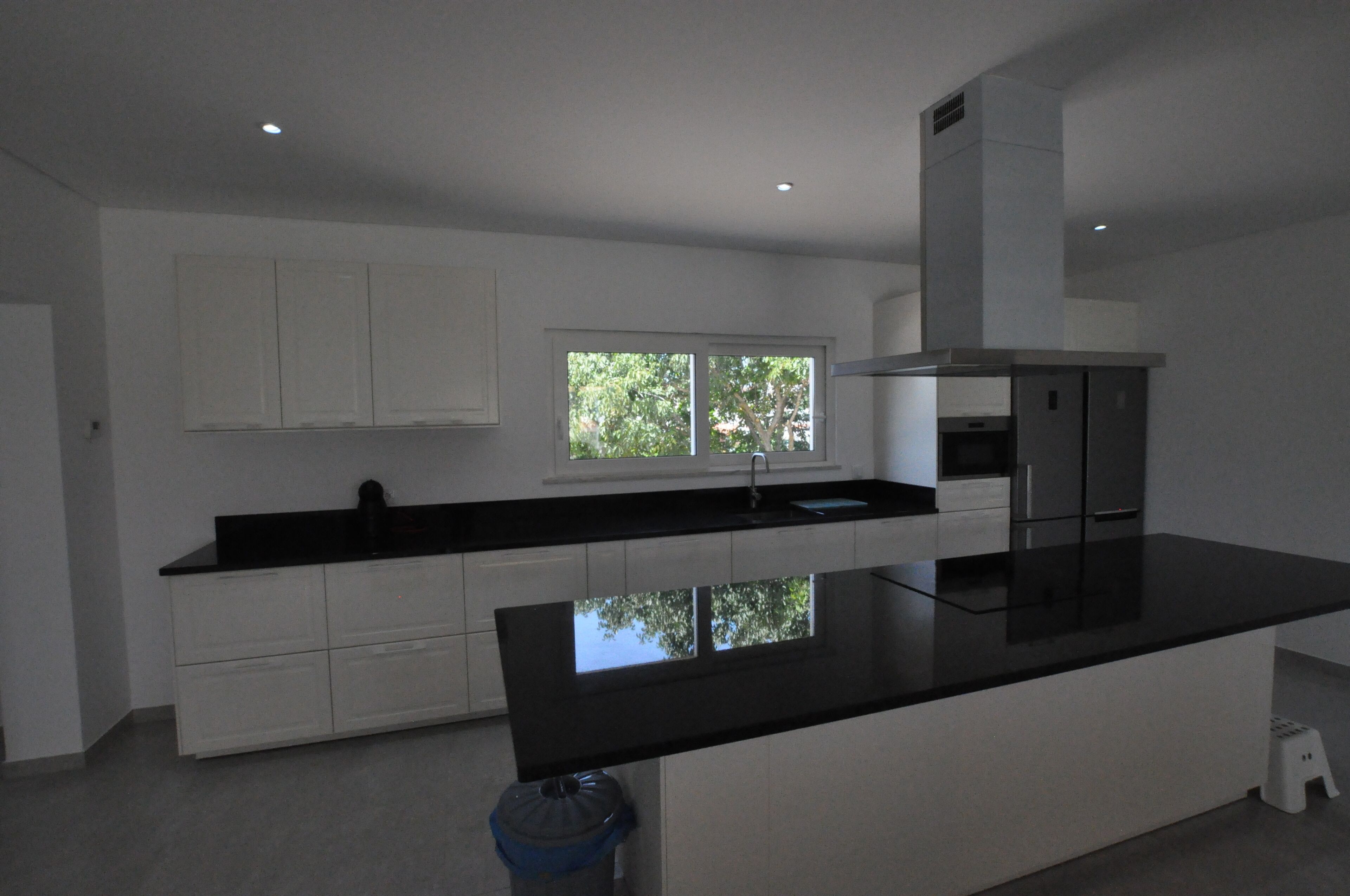 A modern kitchen with white cabinetry, a black countertop, and a window providing natural light.