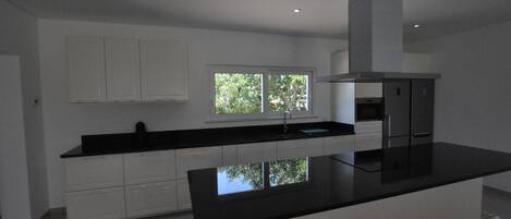 A modern kitchen with white cabinetry, a black countertop, and a window providing natural light.
