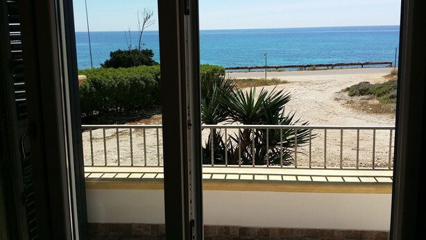 Vista desde un balcón sobre una playa con arena y una valla de madera.