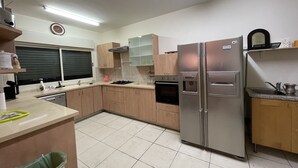Una cucina moderna con mobili in legno, un frigorifero in acciaio inossidabile e una finestra con persiane.