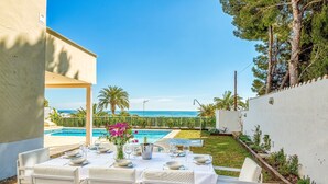 Un espace extérieur aménagé pour les repas, avec vue sur la mer, une piscine et un jardin.