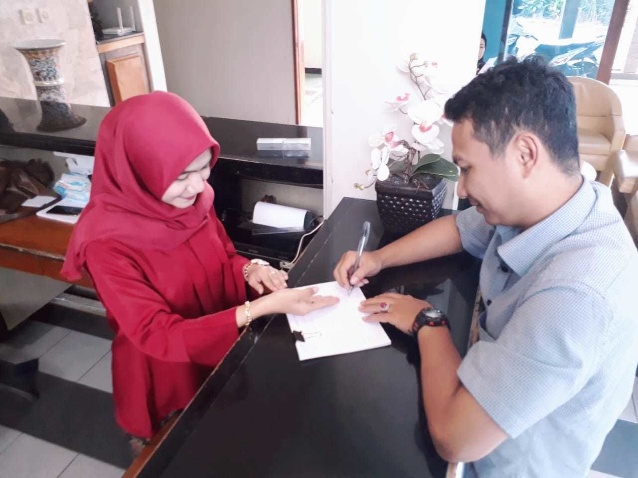 Un mostrador de recepción con una persona firmando un documento.