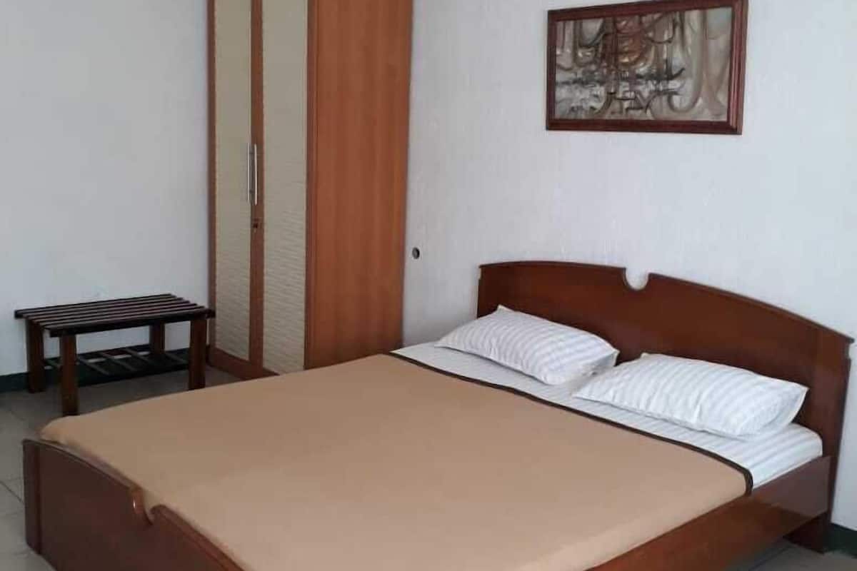 A bedroom with a wooden bed, a wardrobe, and a small table.