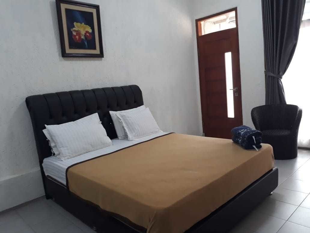 Un dormitorio con una cama, una silla, una puerta y un cuadro en la pared.