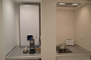 Uma cozinha compacta com cafeteira, torradeira e canecas.