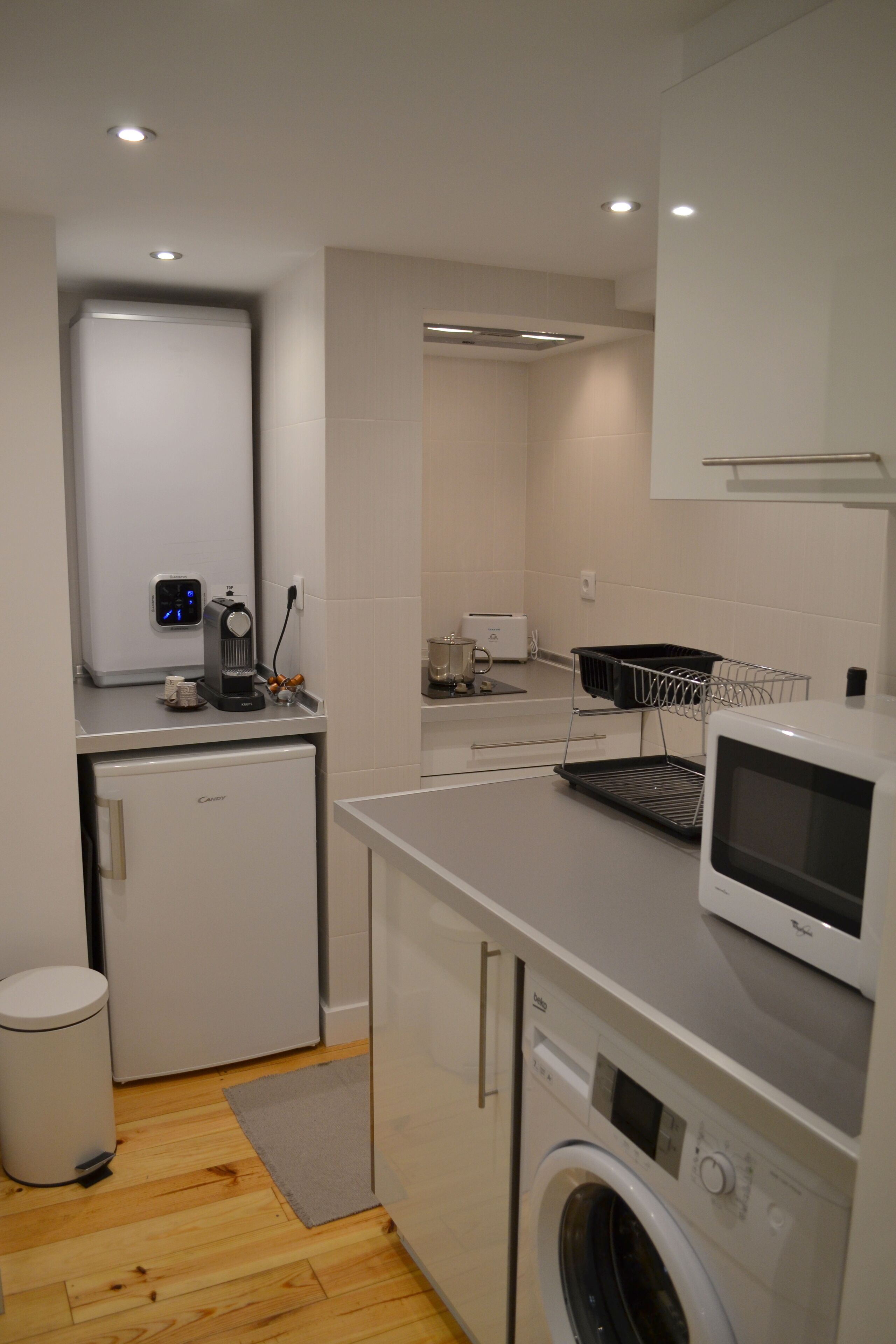 Eine kompakte Küche mit Kühlschrank, Mikrowelle, Toaster und Waschmaschine.
