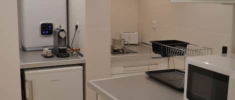 Eine kompakte Küche mit Kühlschrank, Mikrowelle, Toaster und Waschmaschine.