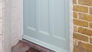 Una puerta azul claro con el número 8, un buzón y un muro de ladrillo.