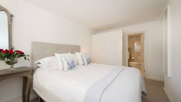 A neatly arranged bedroom with a bed, bedside table, and a mirror.