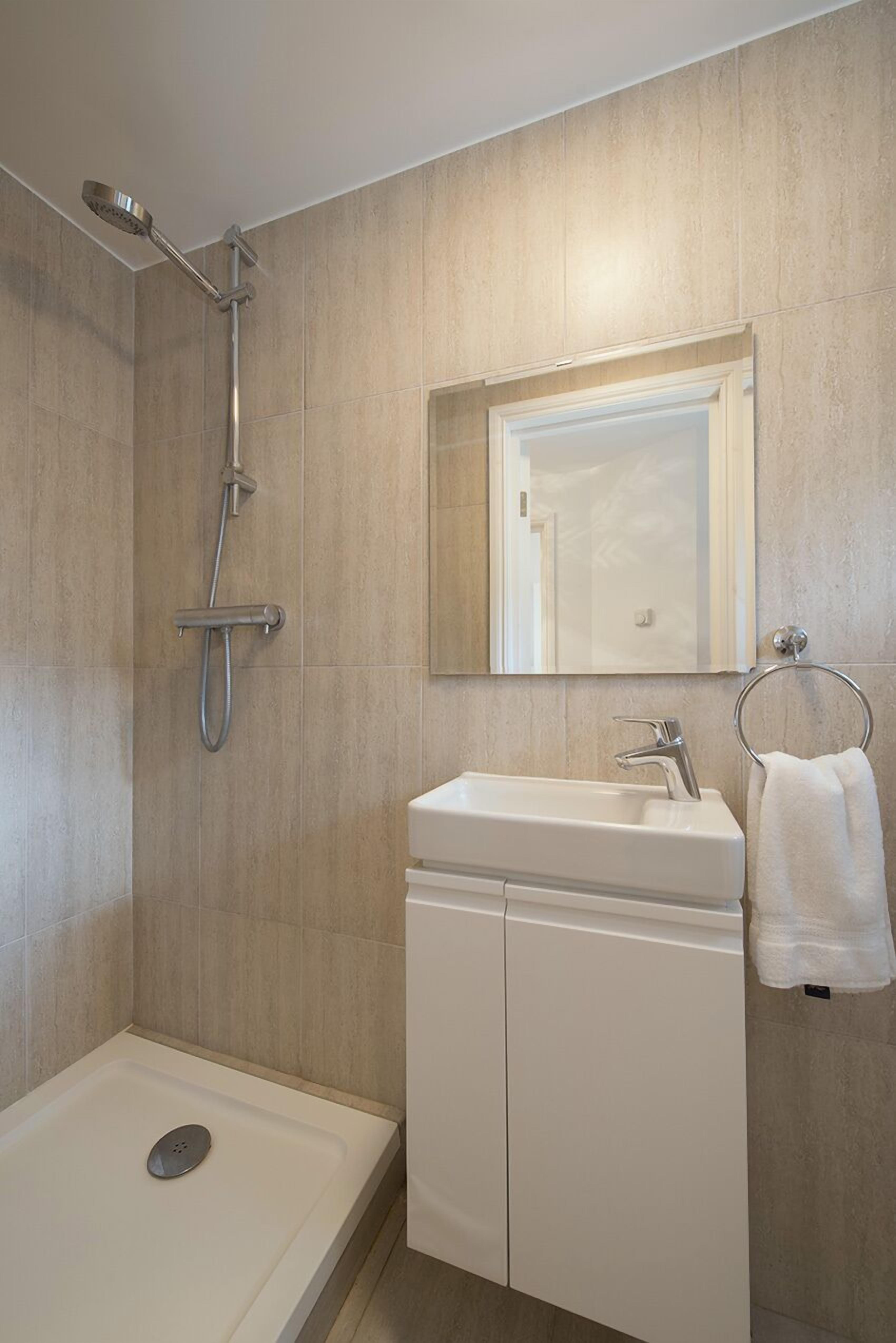 A modern bathroom with a shower, sink, and mirror.