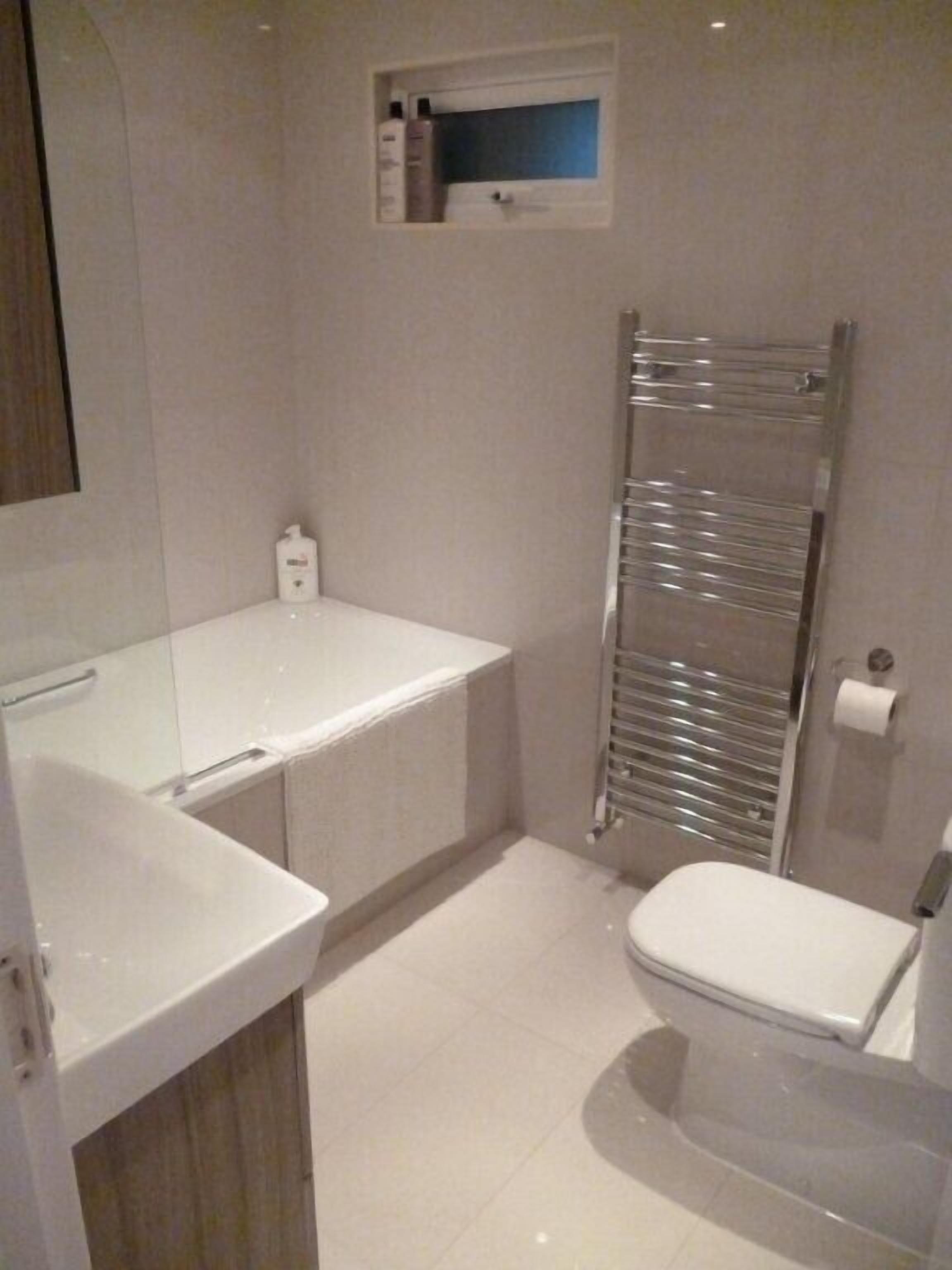 Une salle de bain moderne avec un lavabo blanc, des toilettes et une douche intégrée.