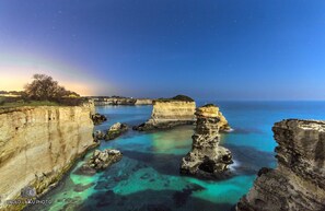 A coastal landscape with clear waters, rocky formations, and a rainbow.