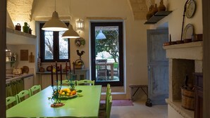 A dining area with a high arched ceiling, a table with chairs, and a view of the outdoors through a window.