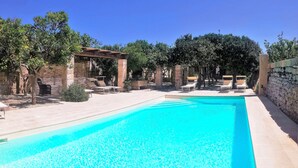 A swimming pool with lounge chairs and a pergola.