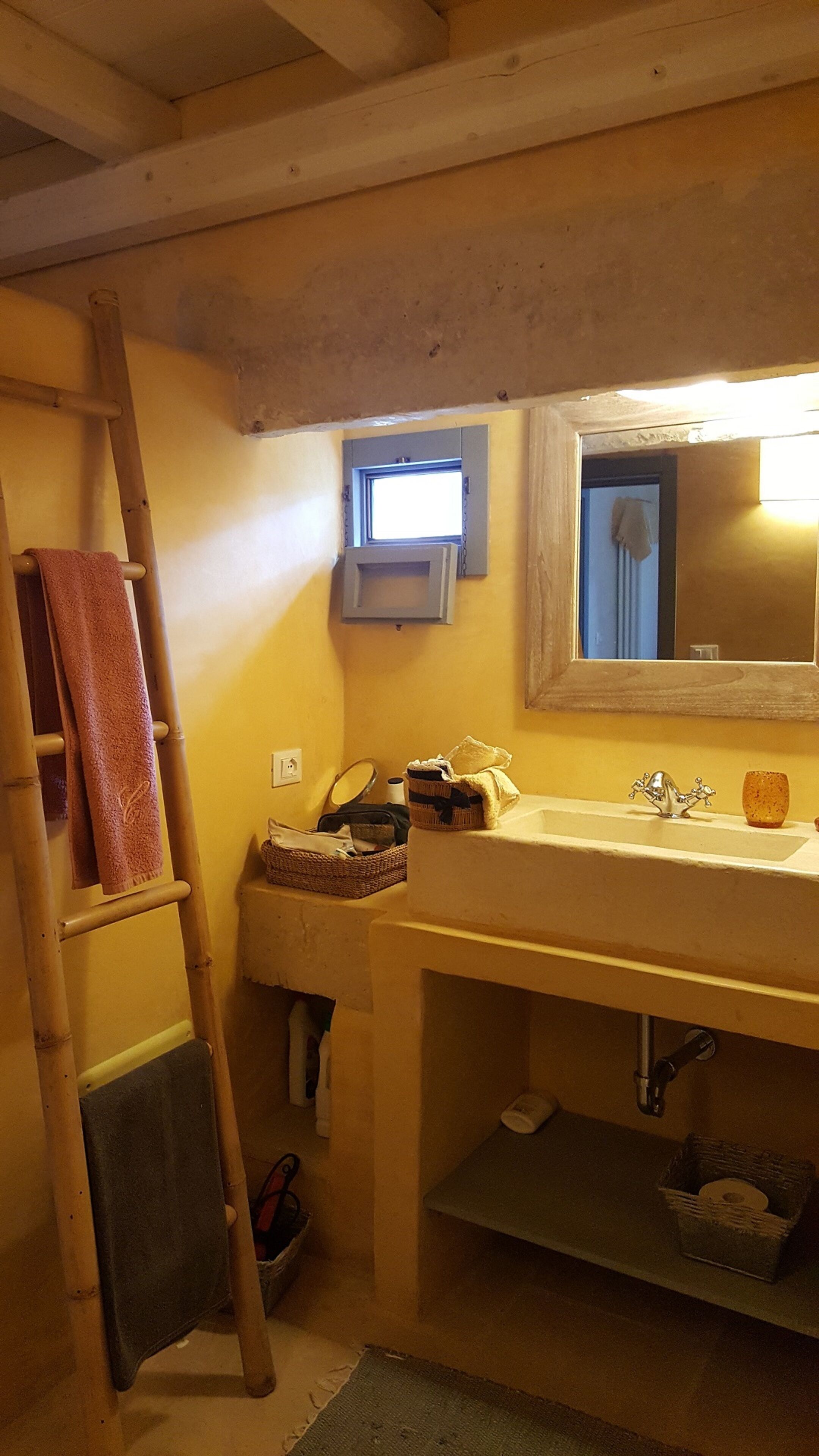 A bathroom with a wooden ladder, a sink, and a mirror.