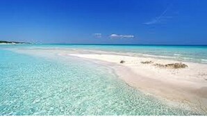 A beach with clear turquoise water and a sandy shore.