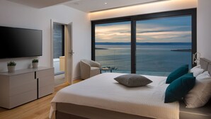 A modern bedroom with a large bed, a TV, and a view of the sea. - Wonderful private villa for 8 guests with private pool, hot tub, WIFI, A/C, TV and terrace (Prigradica)