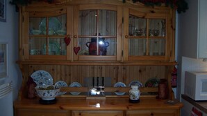 A wooden kitchen with a glass-fronted cabinet above a wooden countertop.