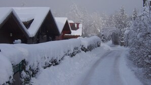 A snow-covered road leading to a row of cabins with pitched roofs.
