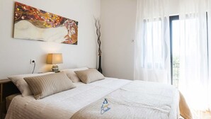 Une chambre à coucher avec un lit, un tableau, une lampe et une fenêtre avec des rideaux.
