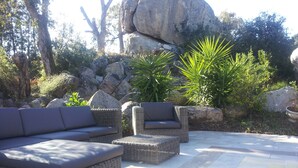 Un patio con mobiliario de mimbre y una piscina.