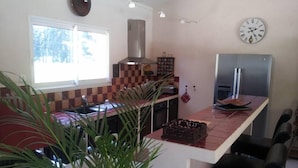 Una cocina moderna con una isla grande, estufa integrada y un refrigerador de acero inoxidable.
