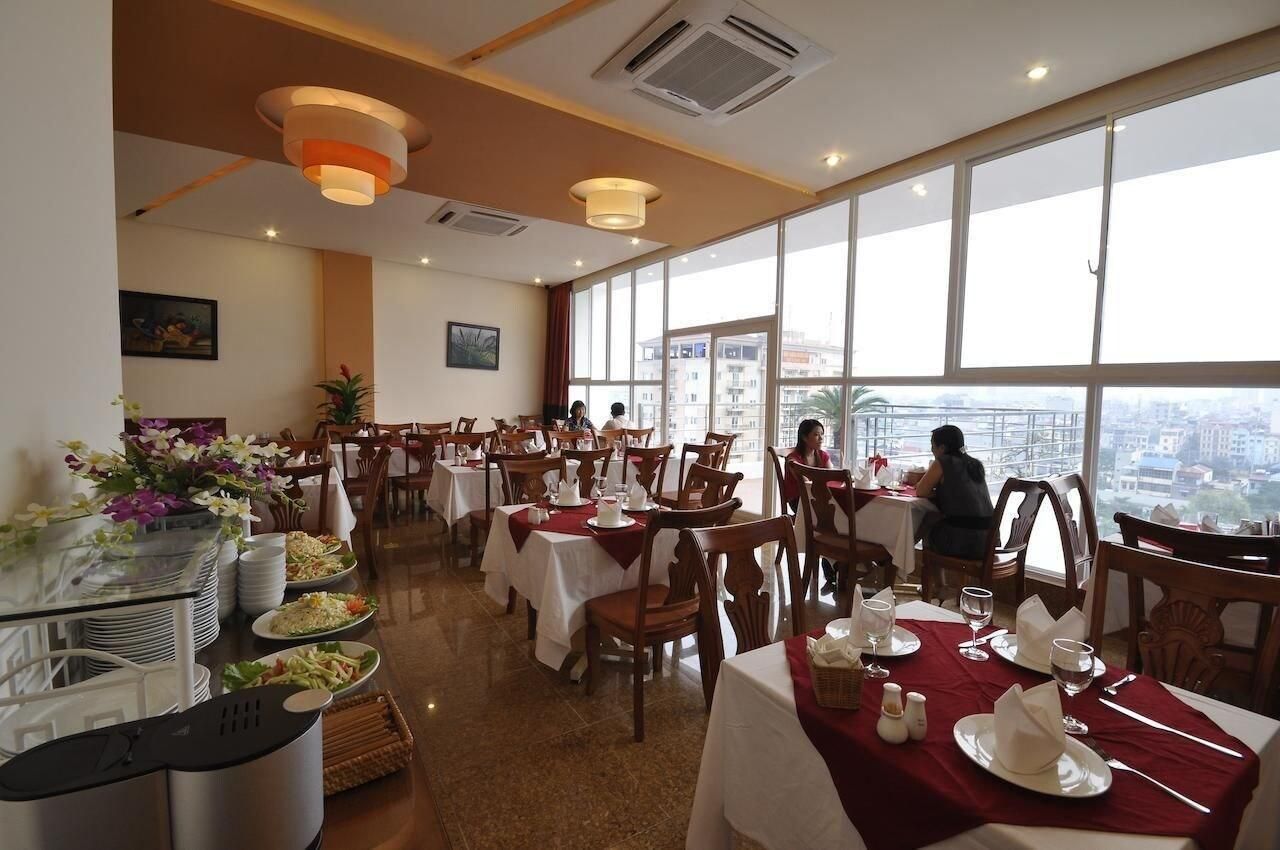 A restaurant with multiple tables, chairs, and a view of the city through large windows.