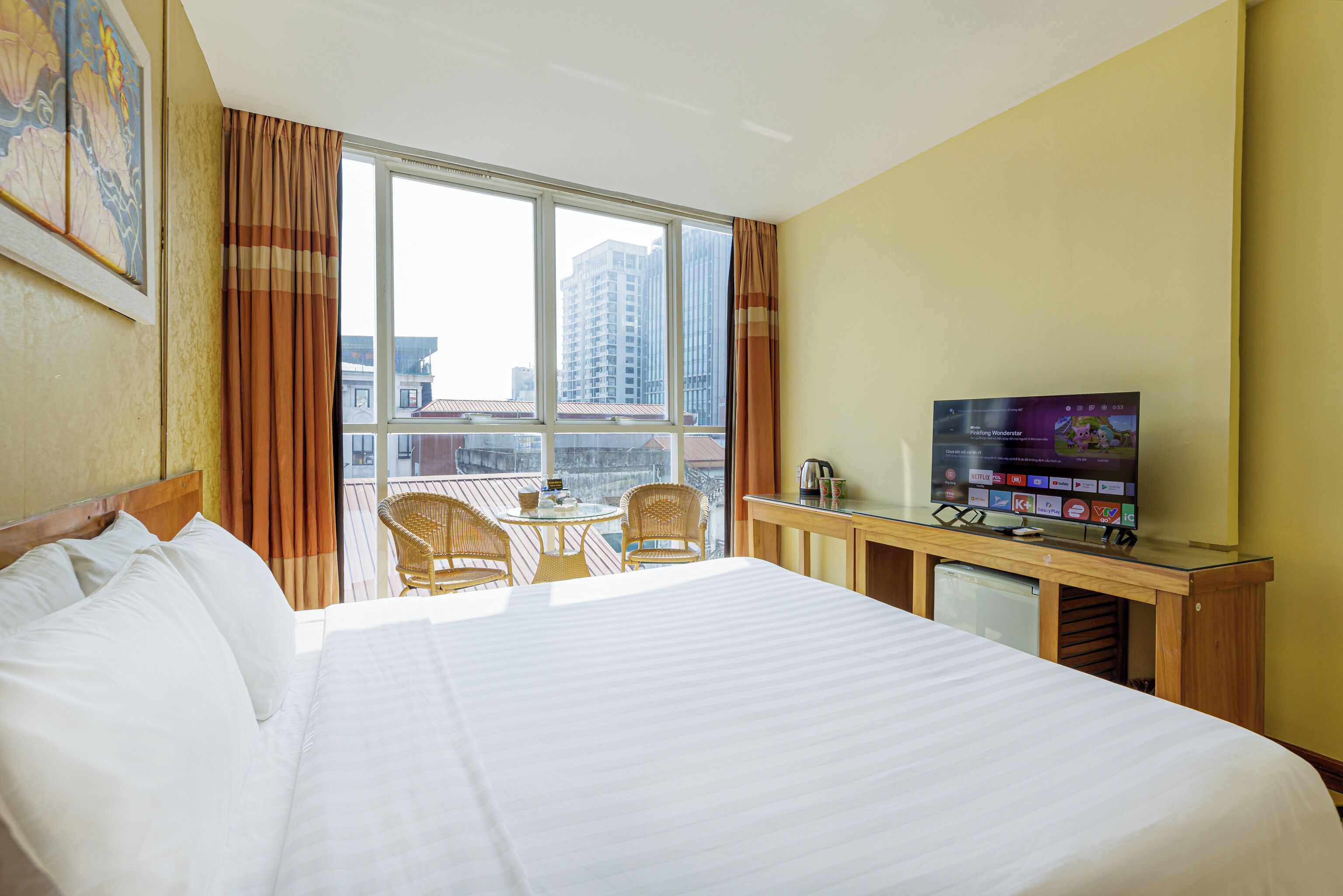 A hotel room with a bed, a TV, a small table, and chairs.