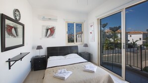 Un dormitorio con cama, mesitas de noche, un ventanal y obras de arte en las paredes.