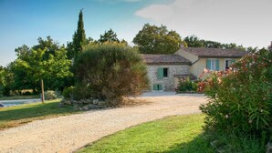 A stone house with a gravel driveway, surrounded by greenery and a clear sky. - Luxury house in 15 acres of land with large private pool (Monteils)