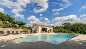 A swimming pool area with lounge chairs, a small building, and a stone wall. - Luxury house in 15 acres of land with large private pool (Monteils)