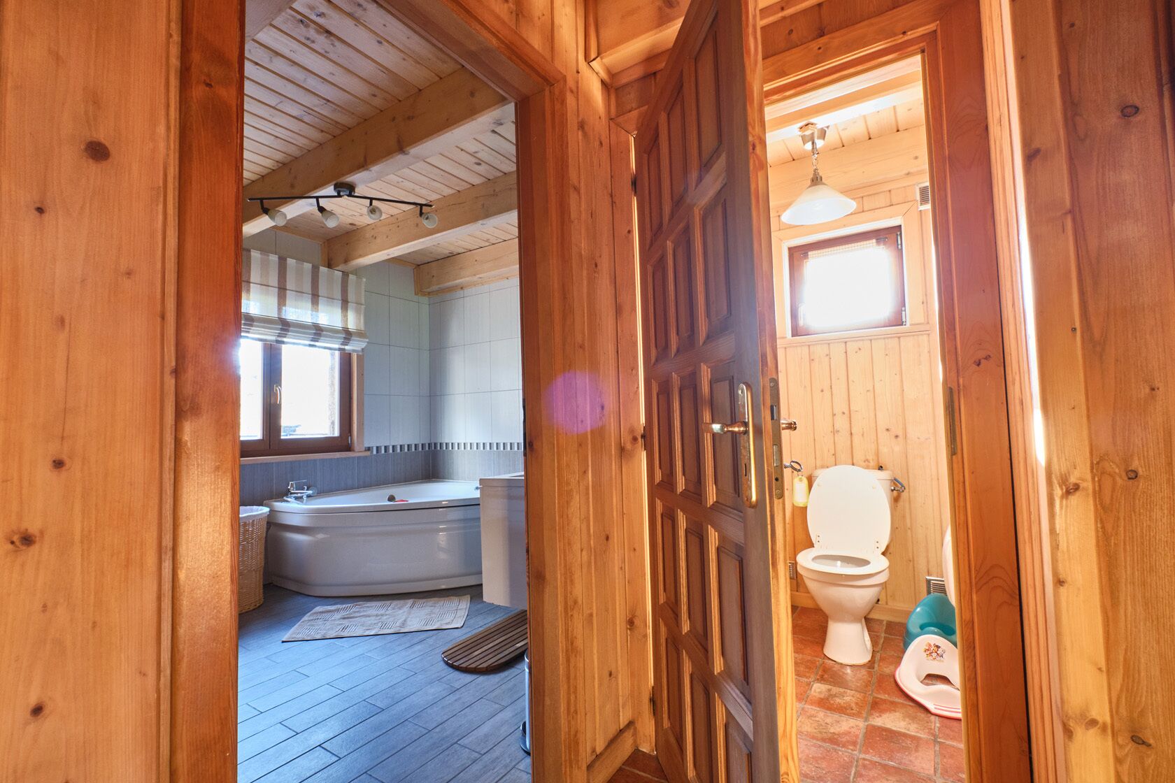 A wooden interior with a bathroom containing a bathtub, toilet, and a child's potty.