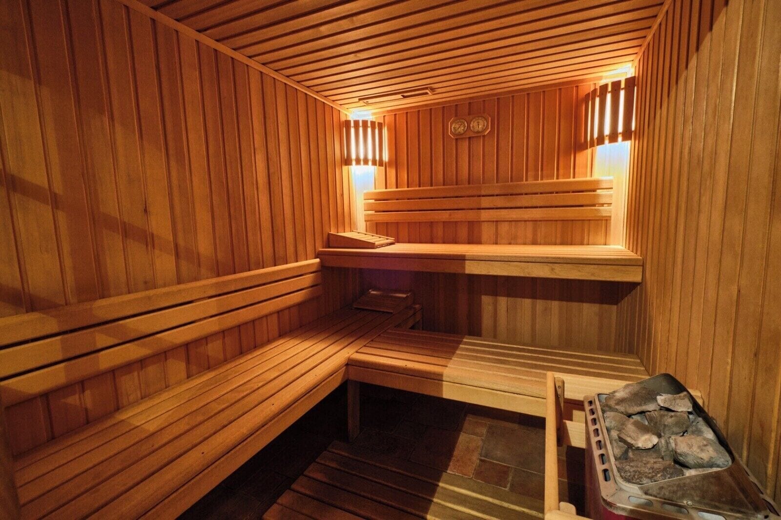 A wooden sauna with benches and a stone heating element.