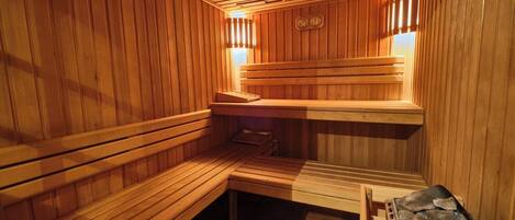 A wooden sauna with benches and a stone heating element.